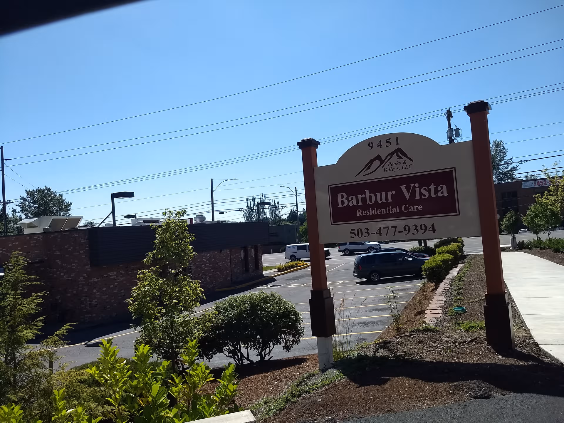 Exterior scene featuring Barbur Vista Residential Care sign near a parking lot.