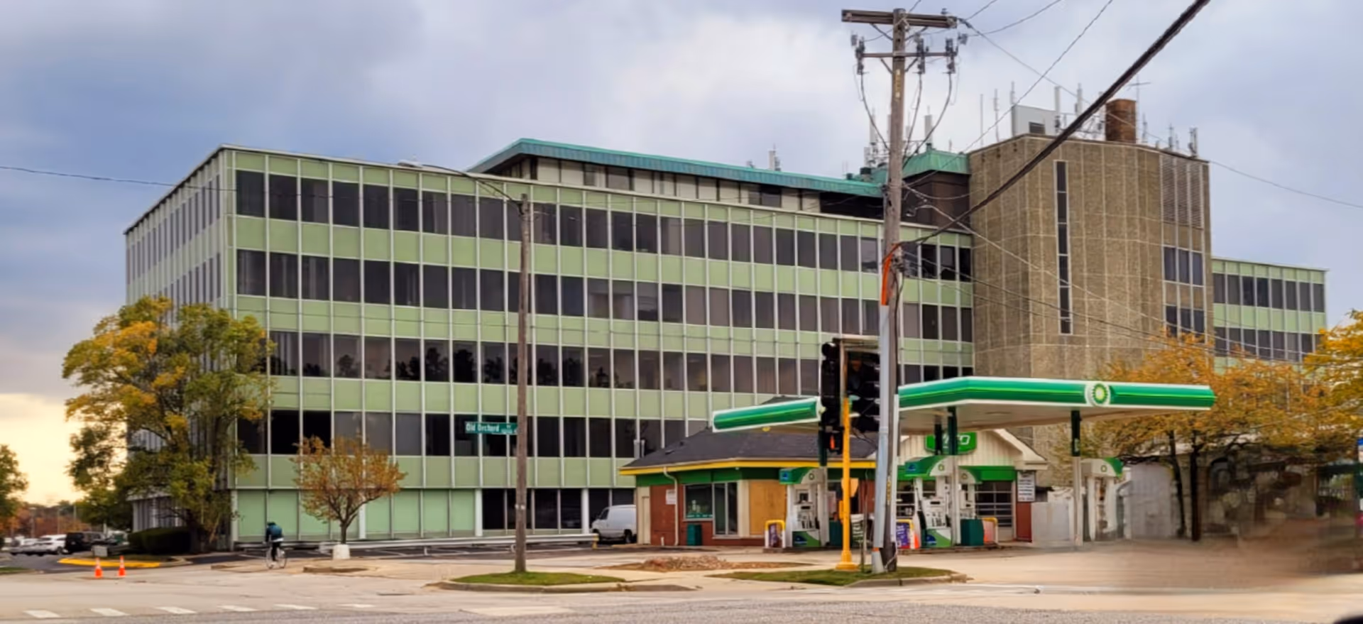 Exterior view of a green-striped, multi-story building with a front gas station.