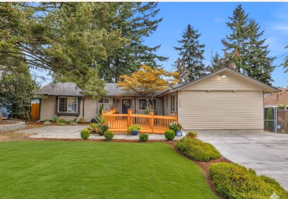 Front view of a single-story senior living home with a wooden porch and lawn.