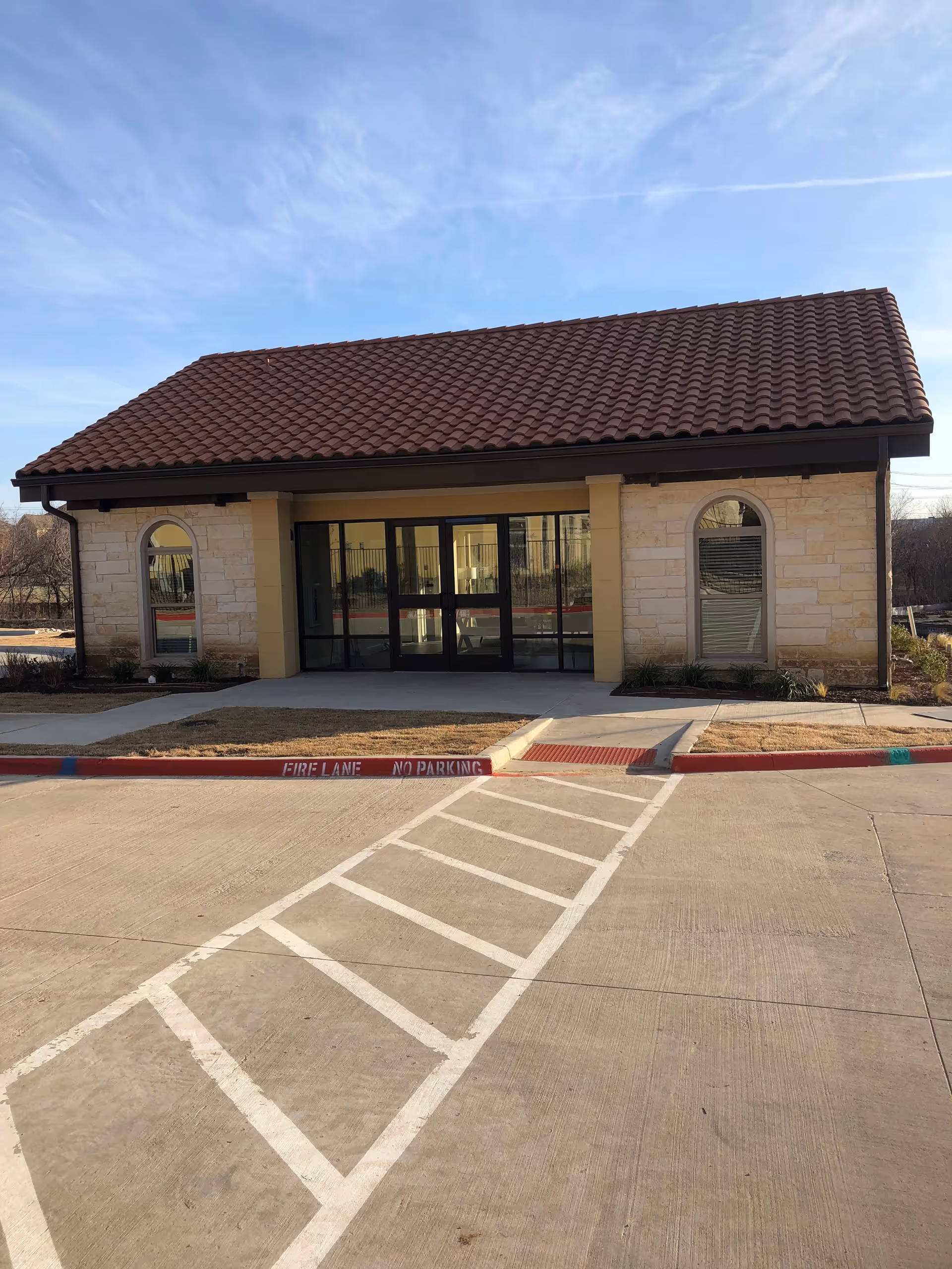 Front view of a single-story building with a red-tiled roof and glass entry doors.