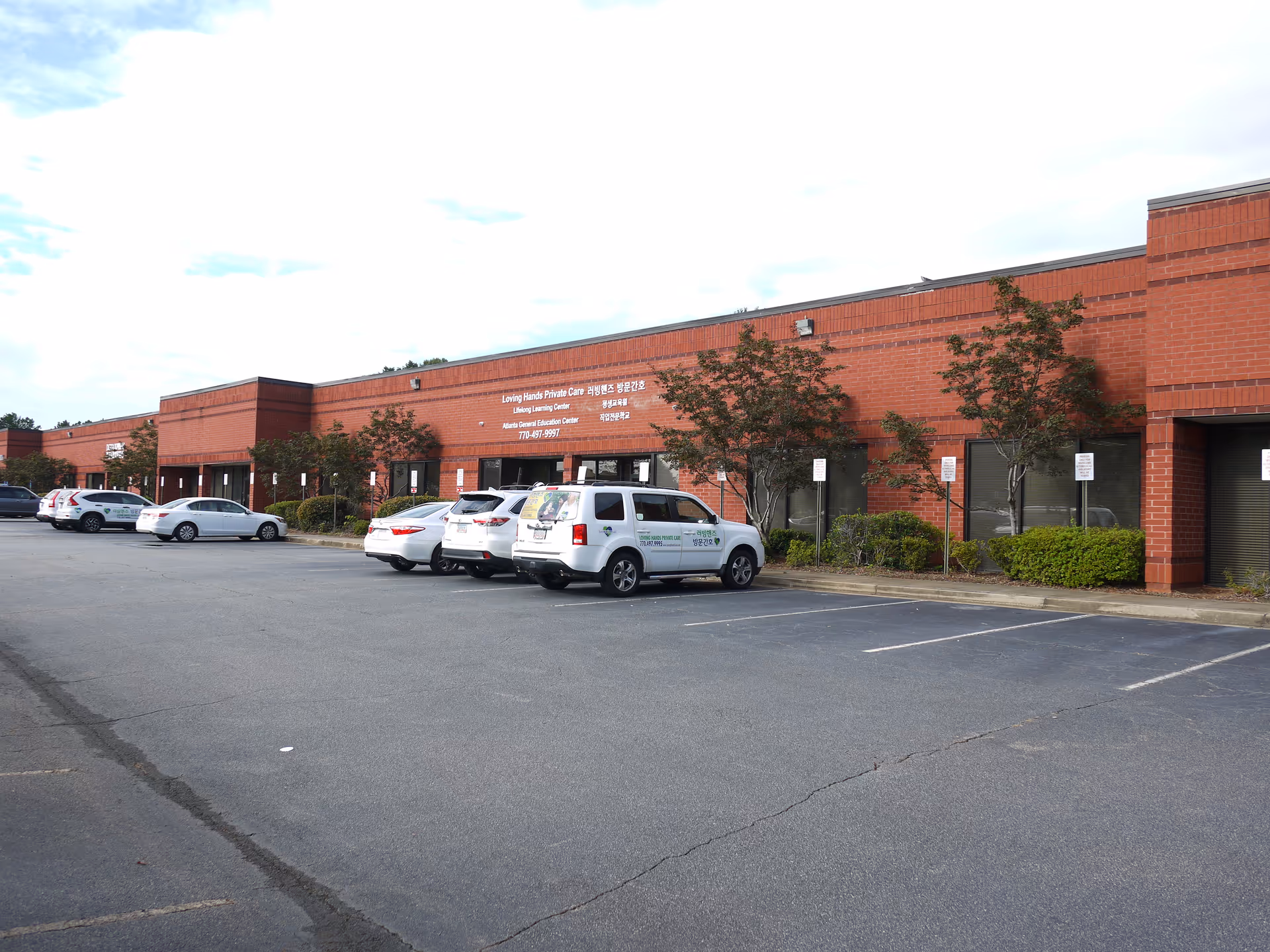 Exterior view of Loving Hands Private Care building with a row of parked cars.