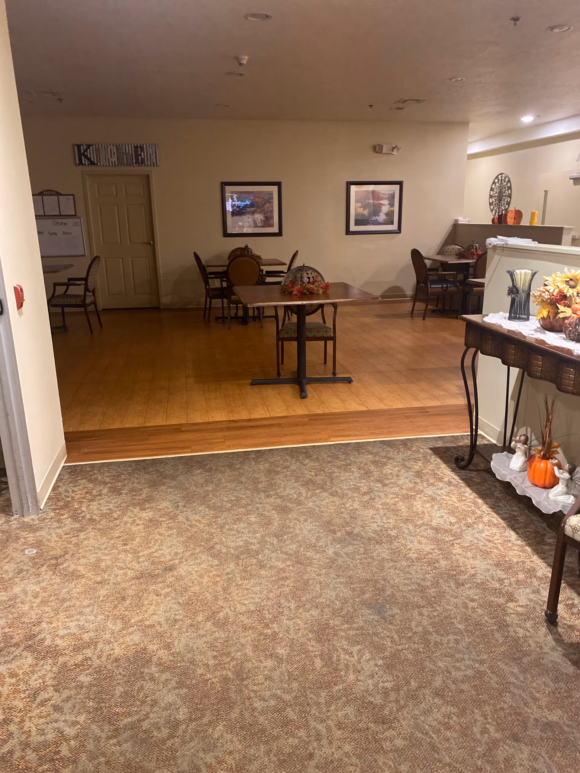 Indoor dining area with wooden floor, several tables and chairs, and wall art.