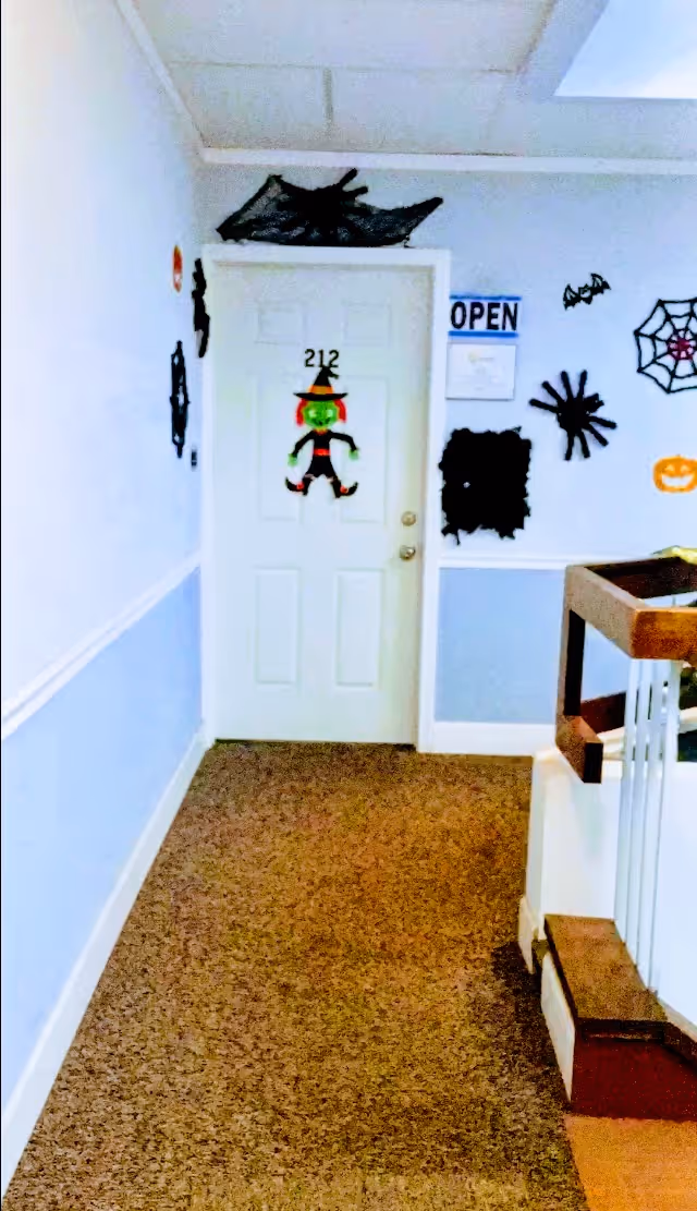 White hallway with a decorated door labeled 212 and Halloween decor.