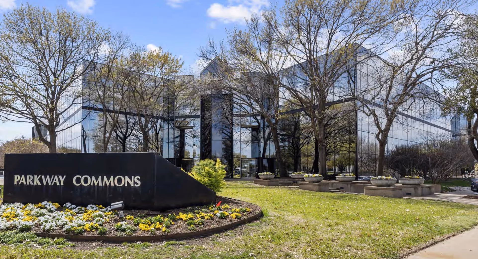 Glass-front building with Parkway Commons sign and landscaped entrance.