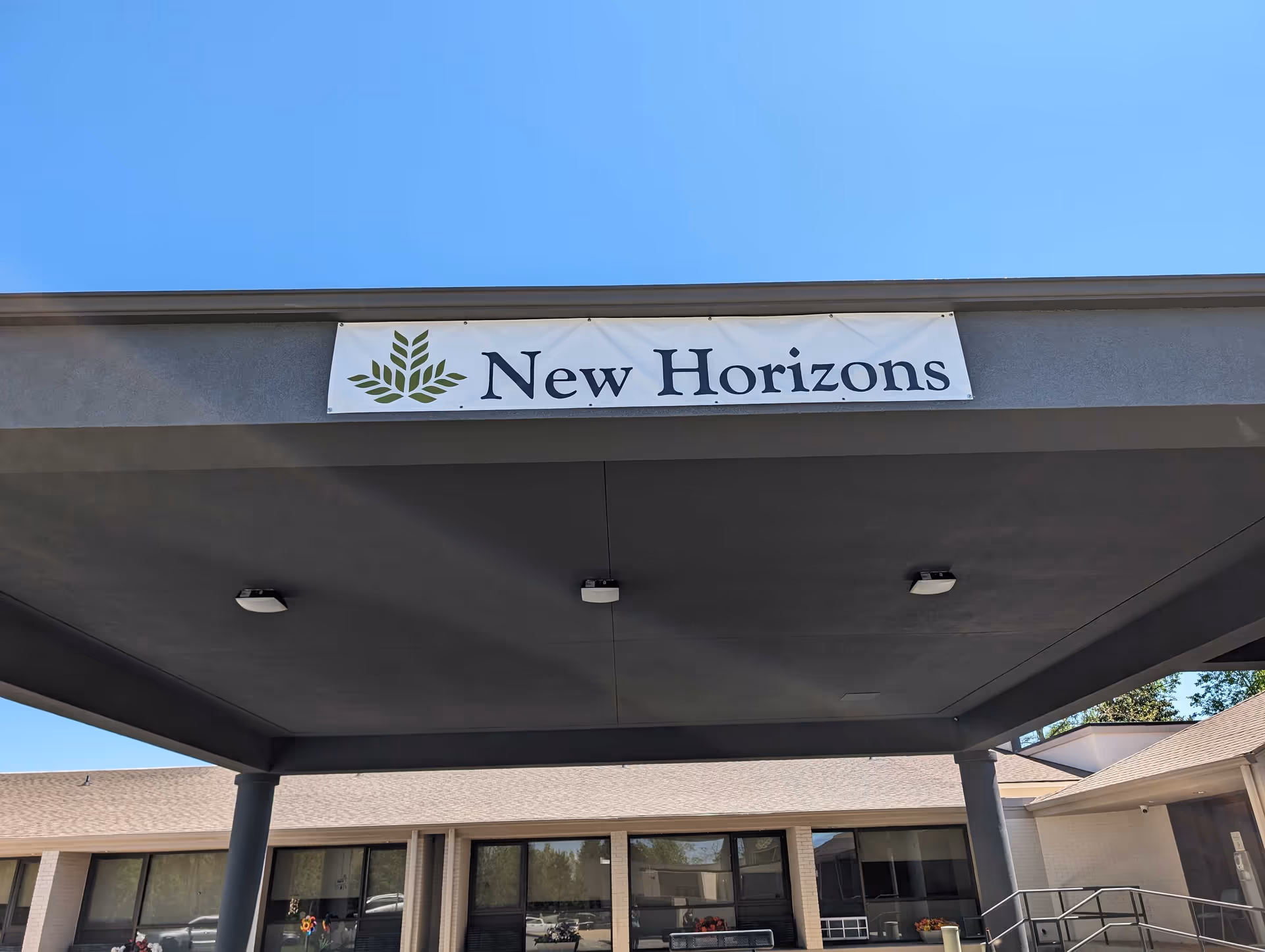 Exterior view of a senior living facility entrance with a New Horizons sign.