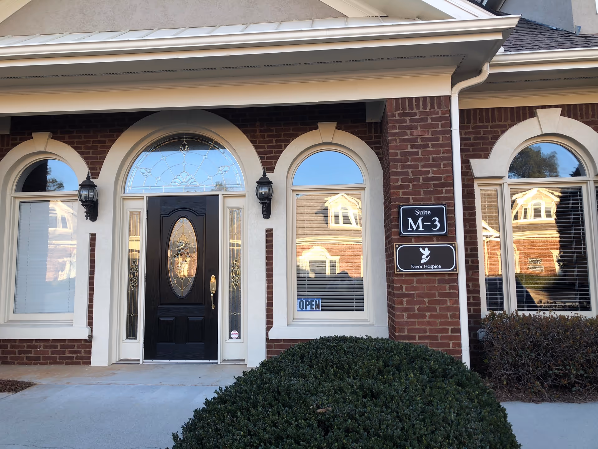 Brick building entrance with arched windows and a black front door.