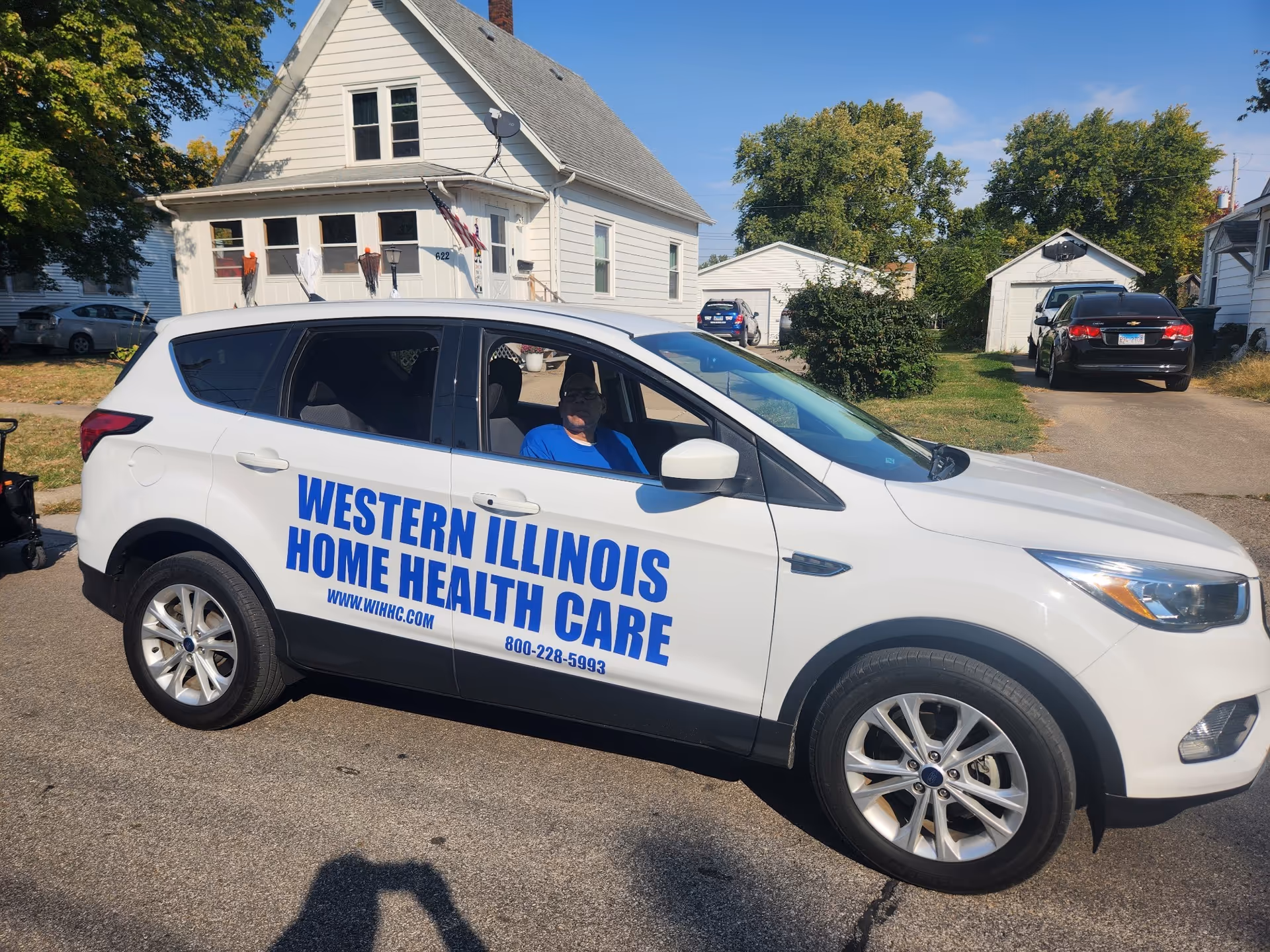 White Western Illinois Home Health Care van parked on a residential street.