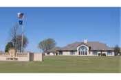 Front exterior of Eagle Estates senior living with flagpoles and green lawn.