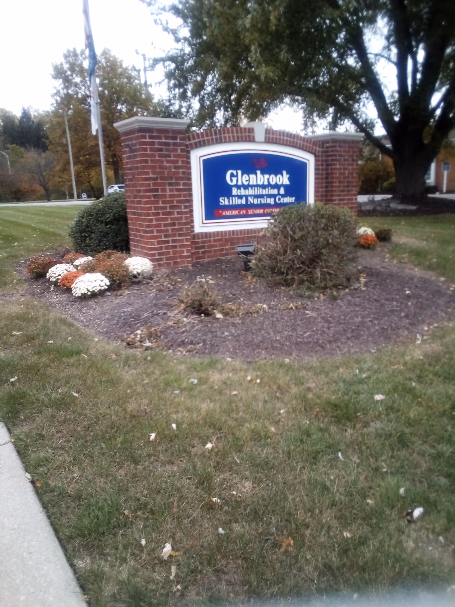 Exterior brick sign for Glenbrook Rehabilitation & Skilled Nursing Center with surrounding shrubs.