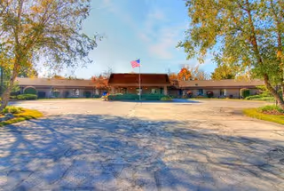 Facade of Valley View Healthcare Center with a flagpole, trees, and a spacious parking lot.