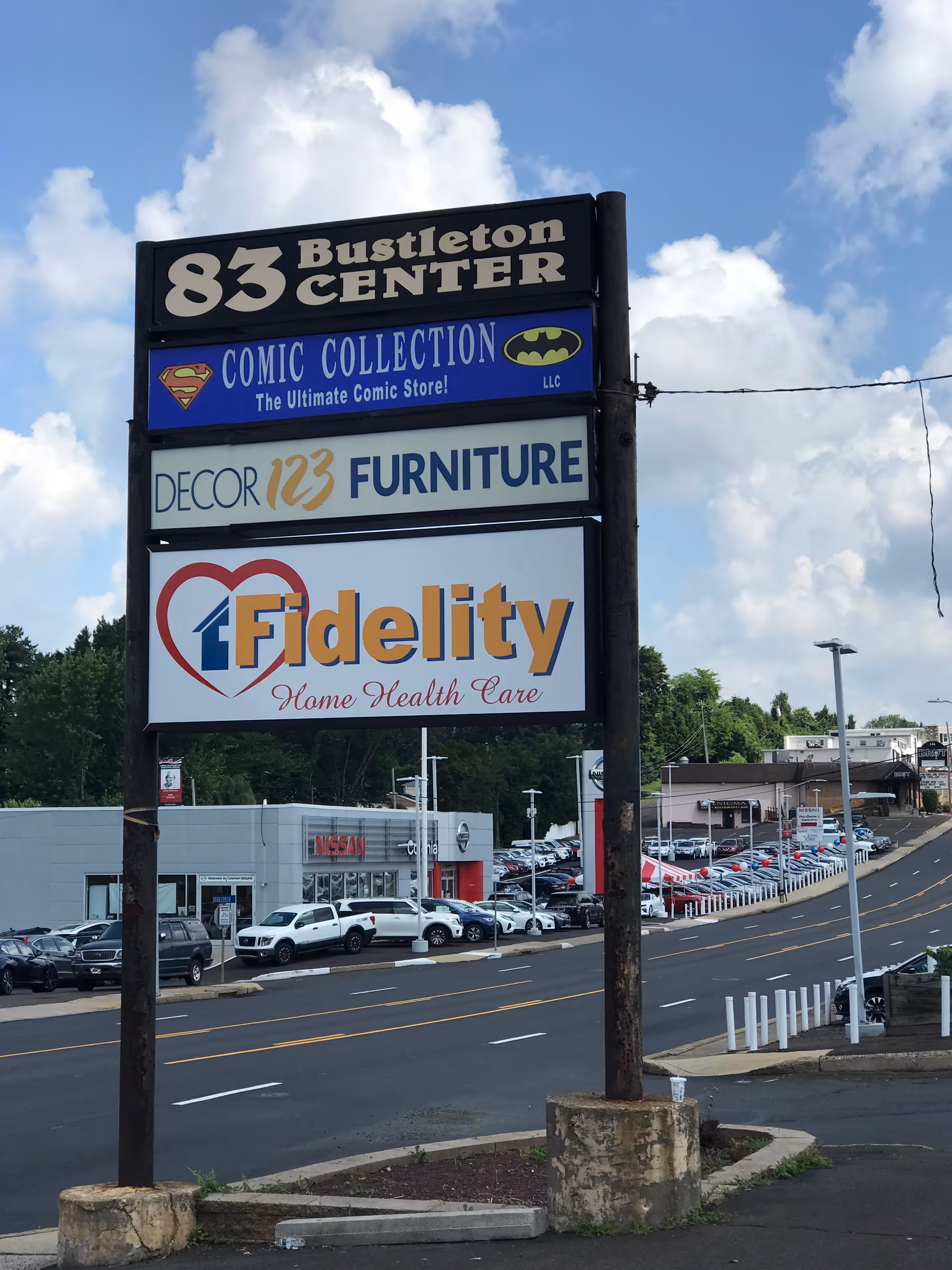 Outdoor signpost displaying Fidelity Home Health Care and other shop signs along a street.