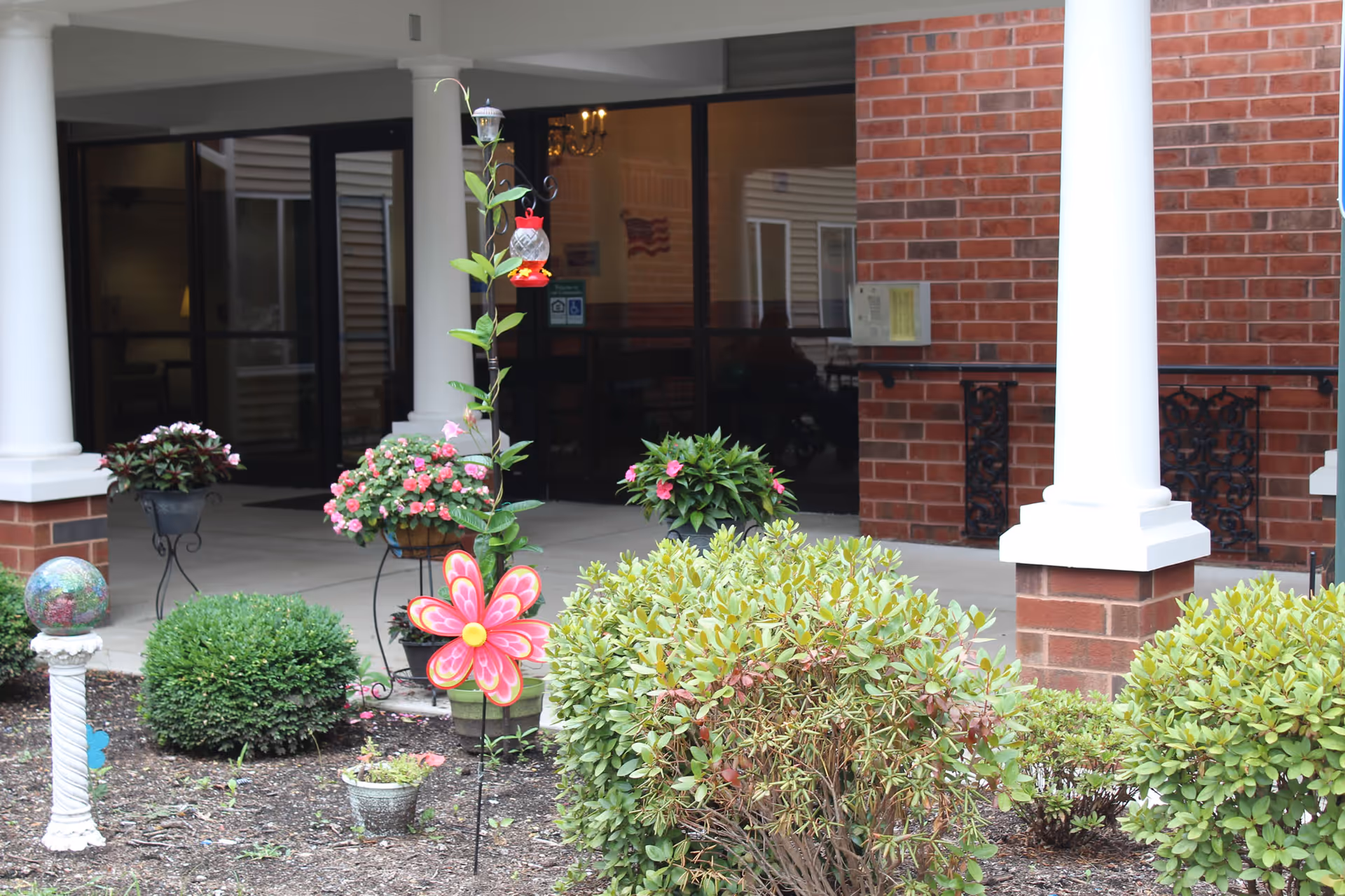 Exterior entrance of St Josephs Apartments with brick walls, white pillars, and landscaped greenery.