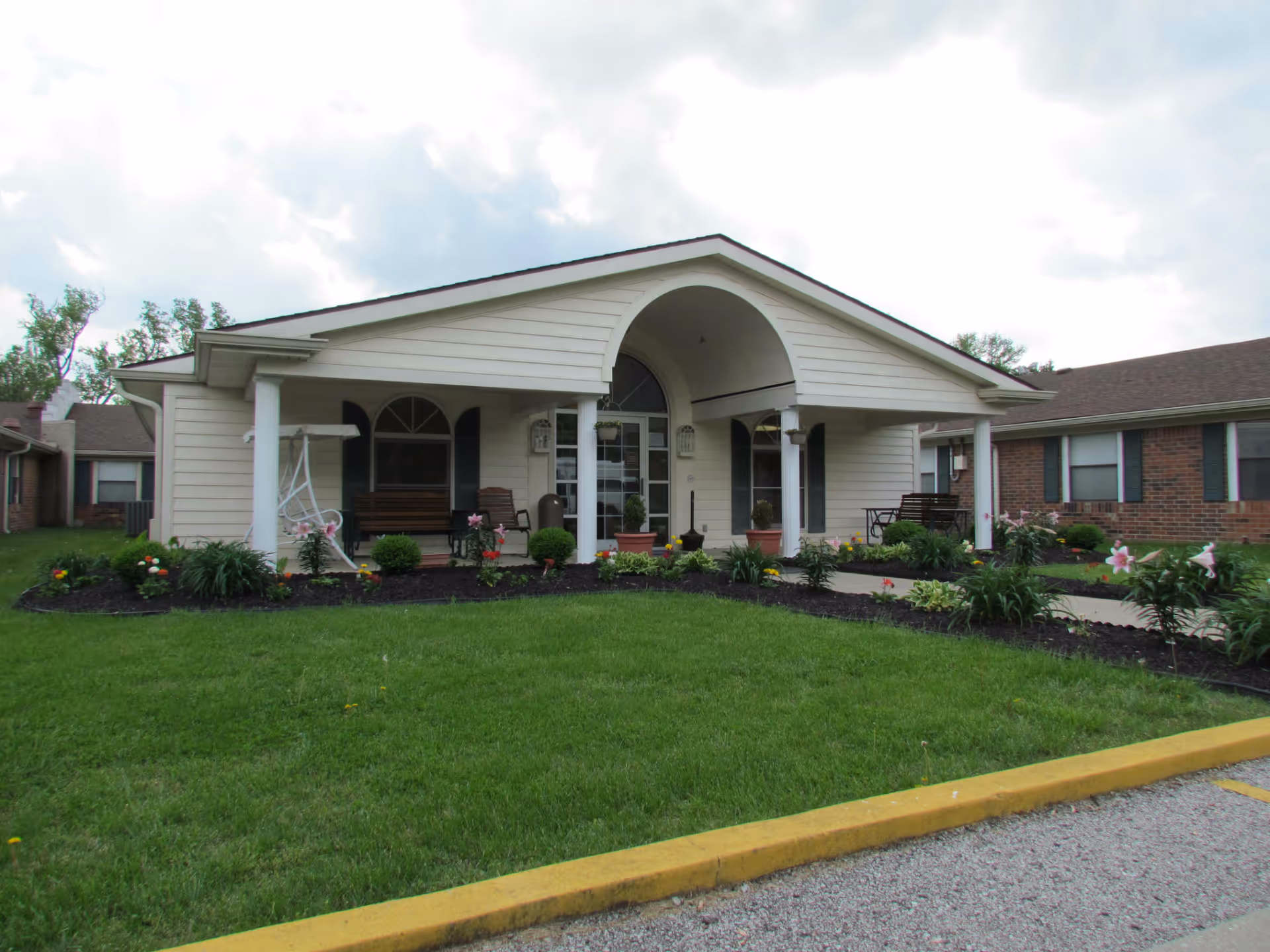 Front view of a single-story senior living facility with a covered porch and garden.