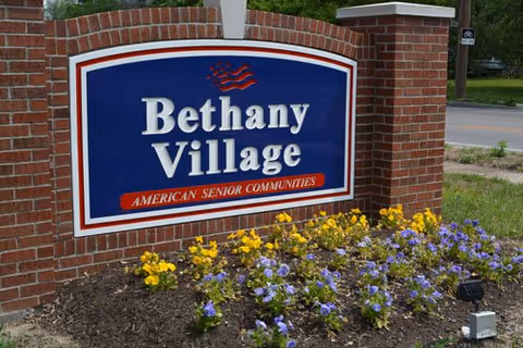 Bethany Village sign on a brick entrance with colorful flowers in front