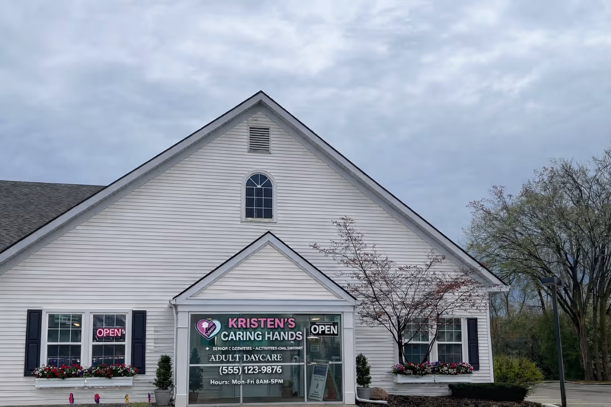 White building with gabled roof and Kristen's Caring Hands storefront signage, surrounded by flower boxes.