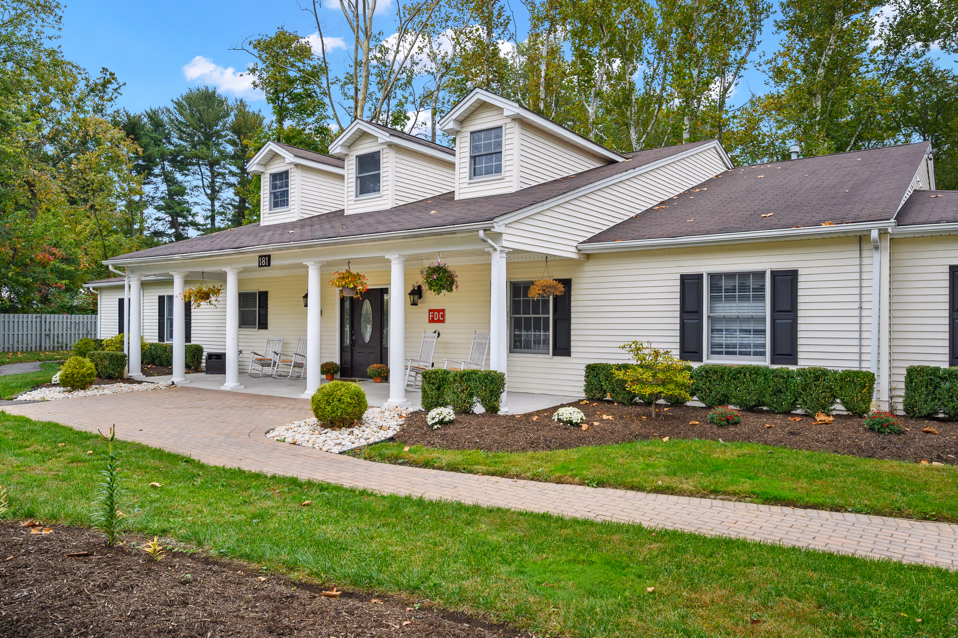 A single-story memory care facility with a covered front porch, columns, and landscaping.
