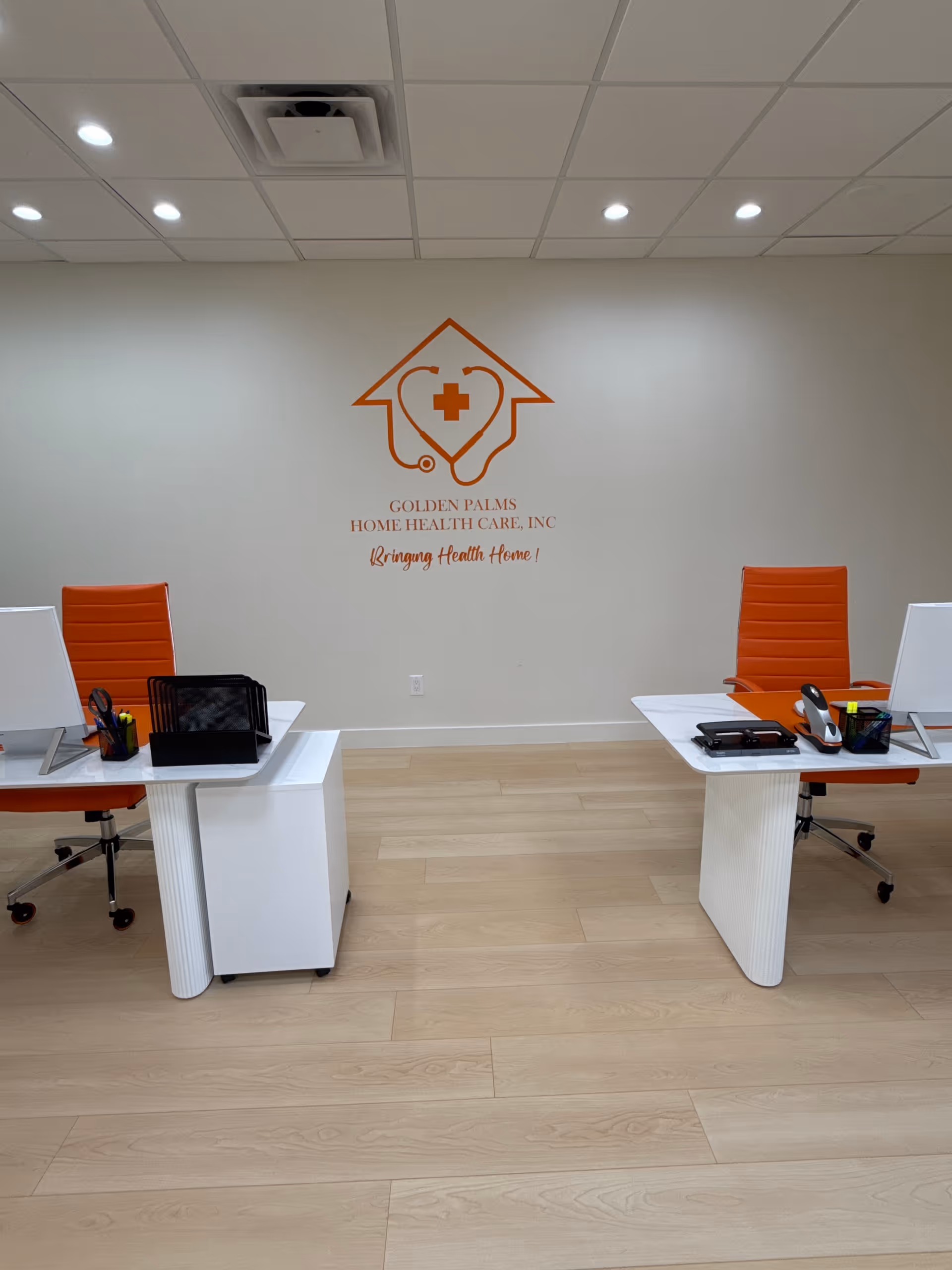 Reception area with white desks, orange chairs, and Golden Palms logo on wall.