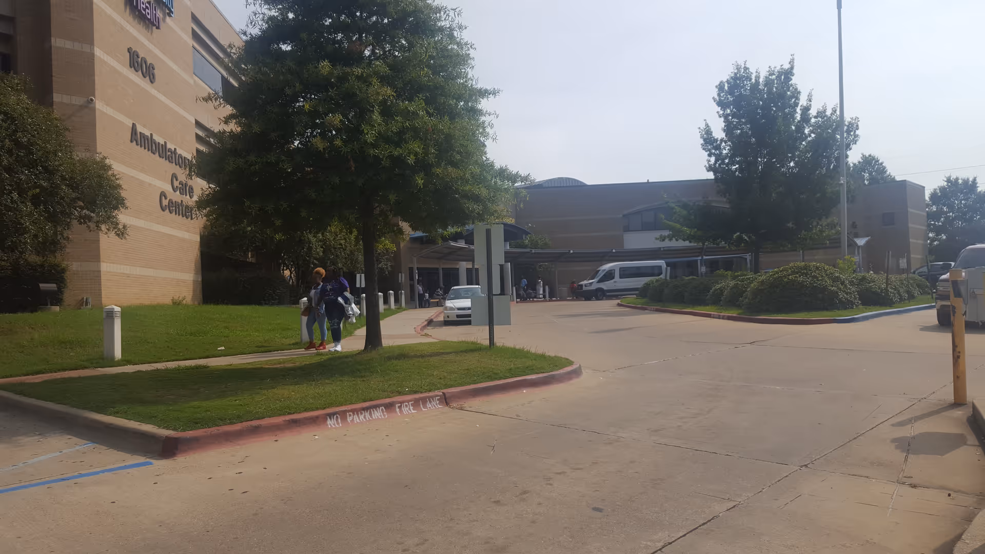Exterior view of Ochsner LSU Health Ambulatory Care Center with driveway, trees, and people near entrance.