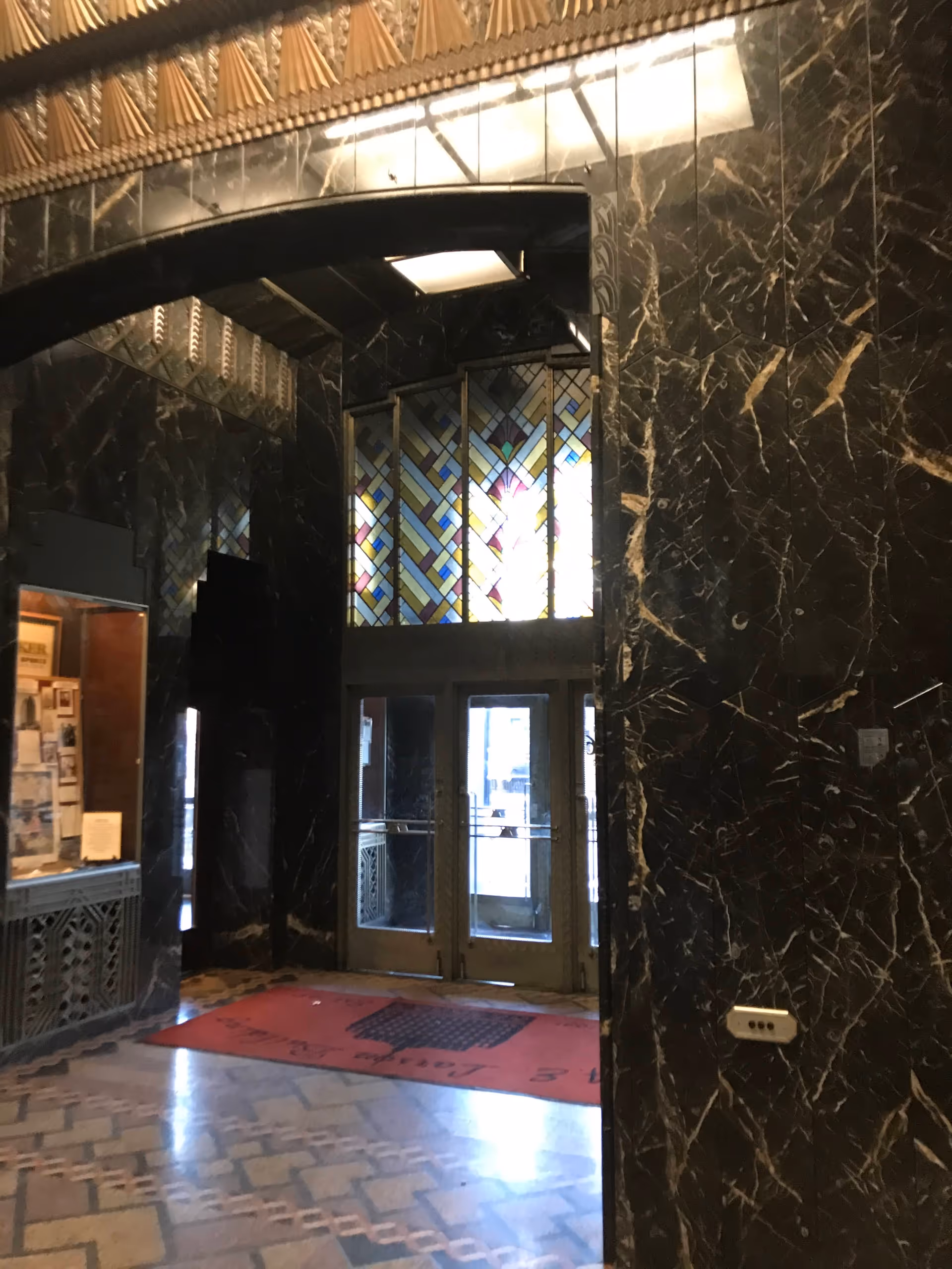 Luxurious marble lobby with an arched doorway, stained glass, and double doors.