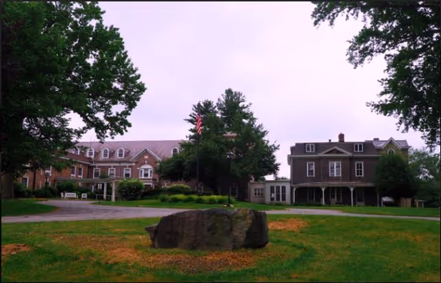 Weston Senior Living Center at Highfield campus with brick buildings, lawn, trees, and flagpole.