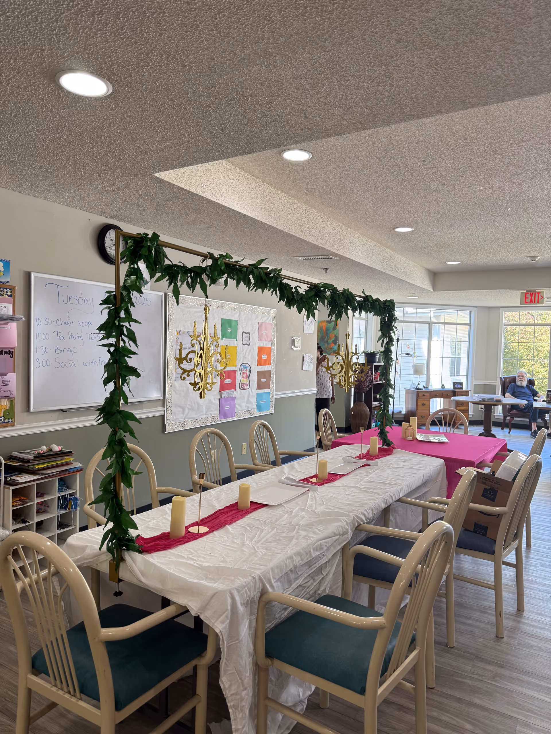 Garland arch over a long dining table set with candles in a bright dining room.