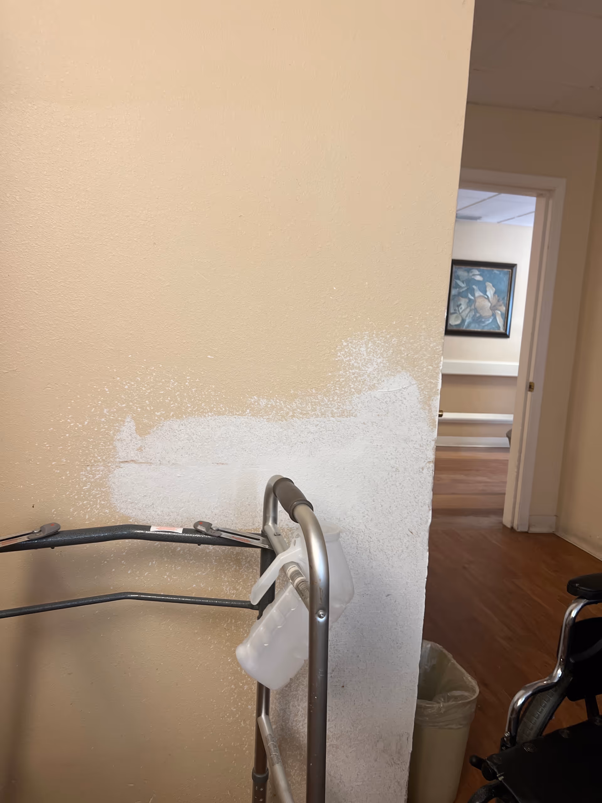 Interior hallway in a senior facility with a walker and a chipped painted wall.