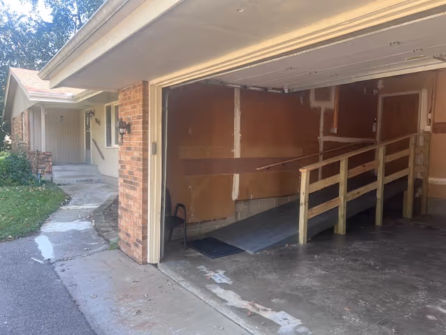 Exterior view of a senior living facility entrance with a ramp and brick walls.