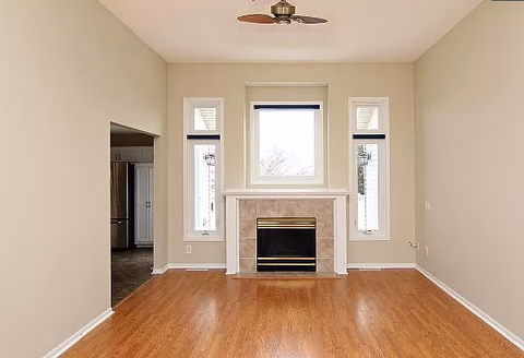 Bright living room with hardwood floors, a fireplace, and tall windows.