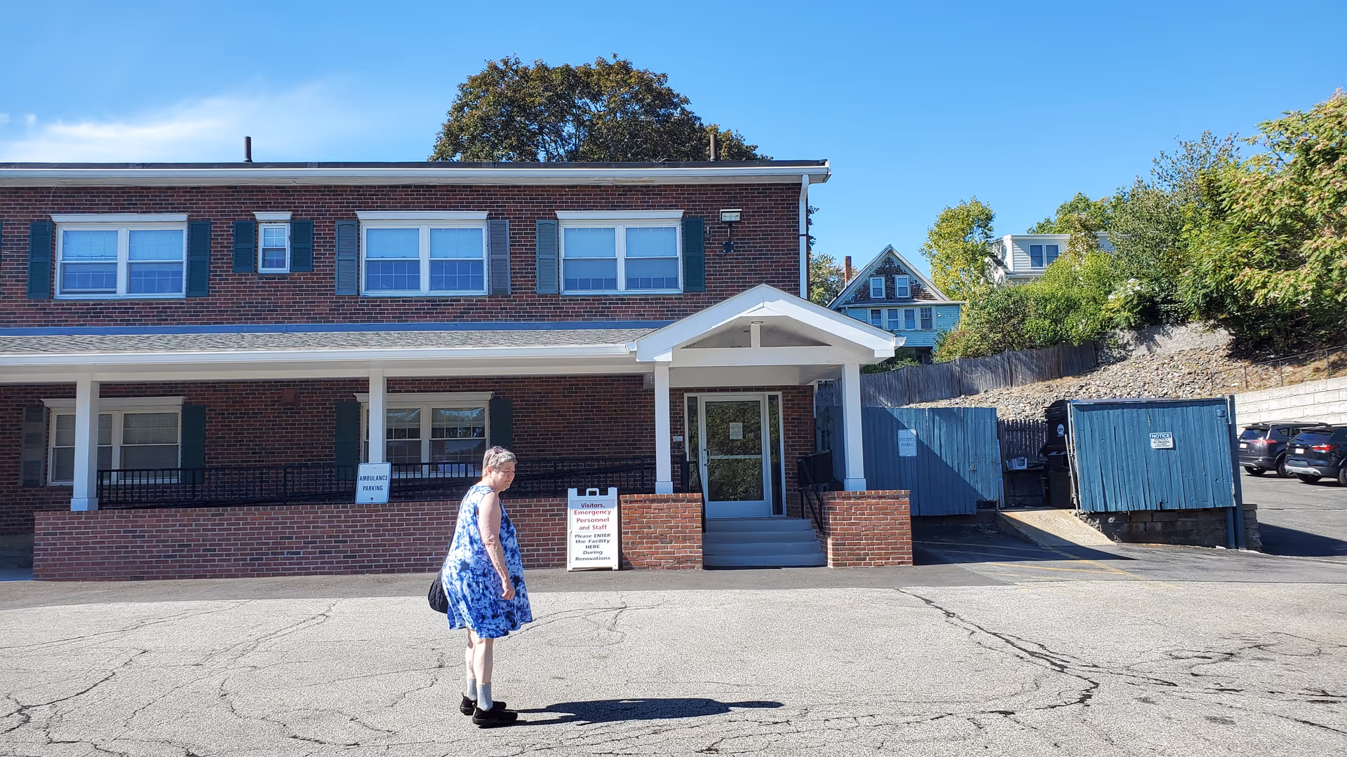 Winchester Nursing Center brick building with a covered entrance and a woman walking.
