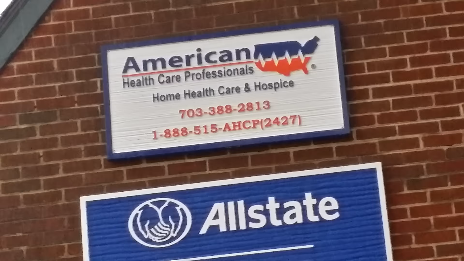 Brick exterior wall with American Healthcare Professionals and Allstate signs mounted on building.