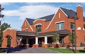Red brick senior living facility with a covered entrance and landscaping.