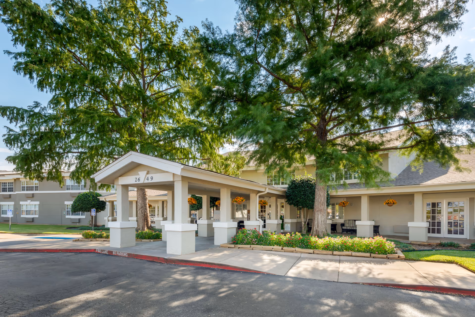 Exterior view of Brookdale Sikes Lake entrance with a canopy, drive, and landscaping.