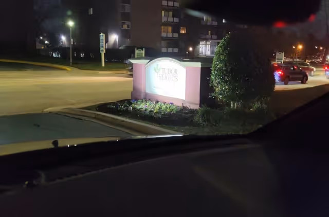 Night exterior of Aventura at the Heights entrance with a lit sign.