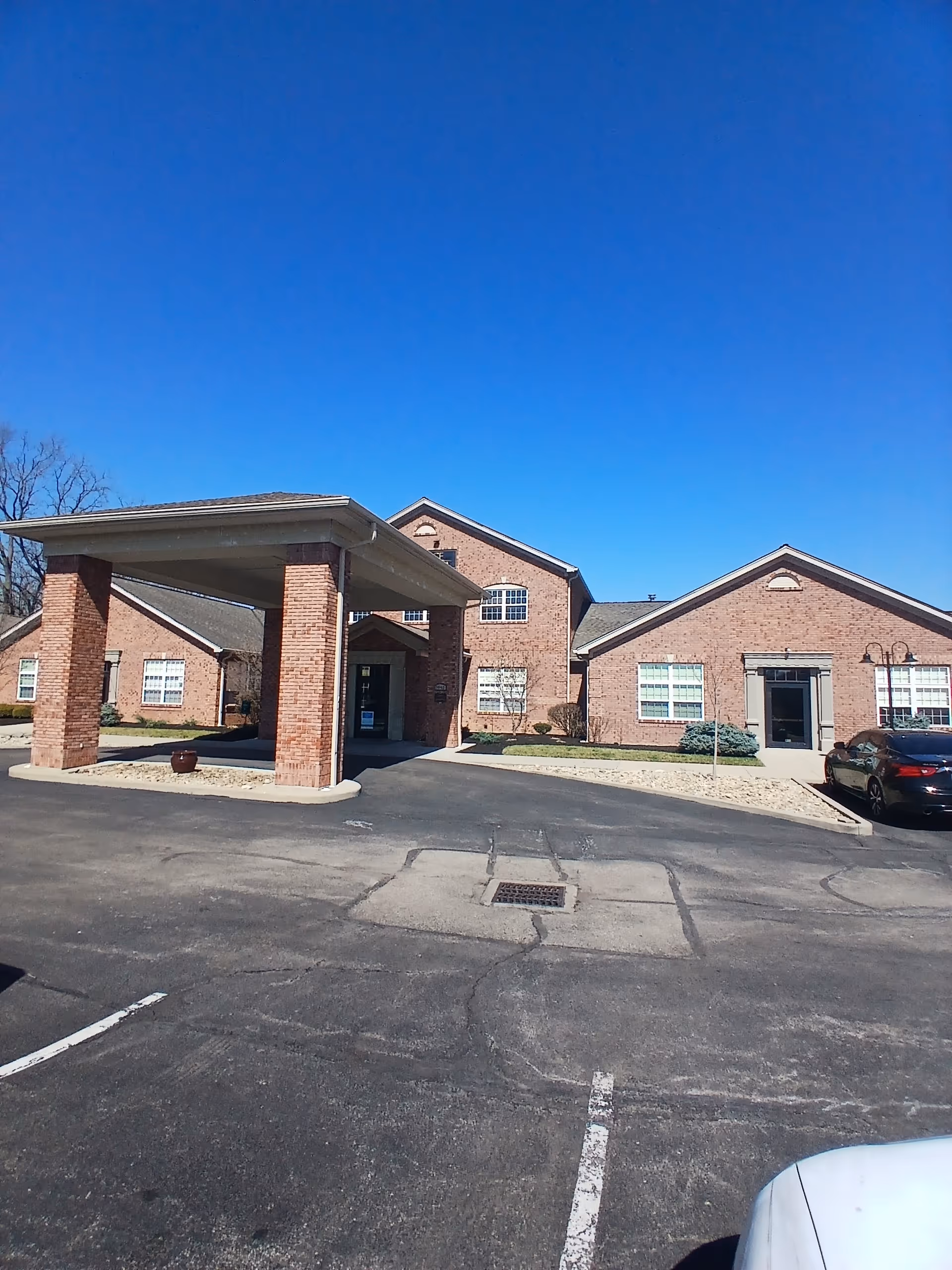 Brick senior living facility with a covered entrance and surrounding parking.