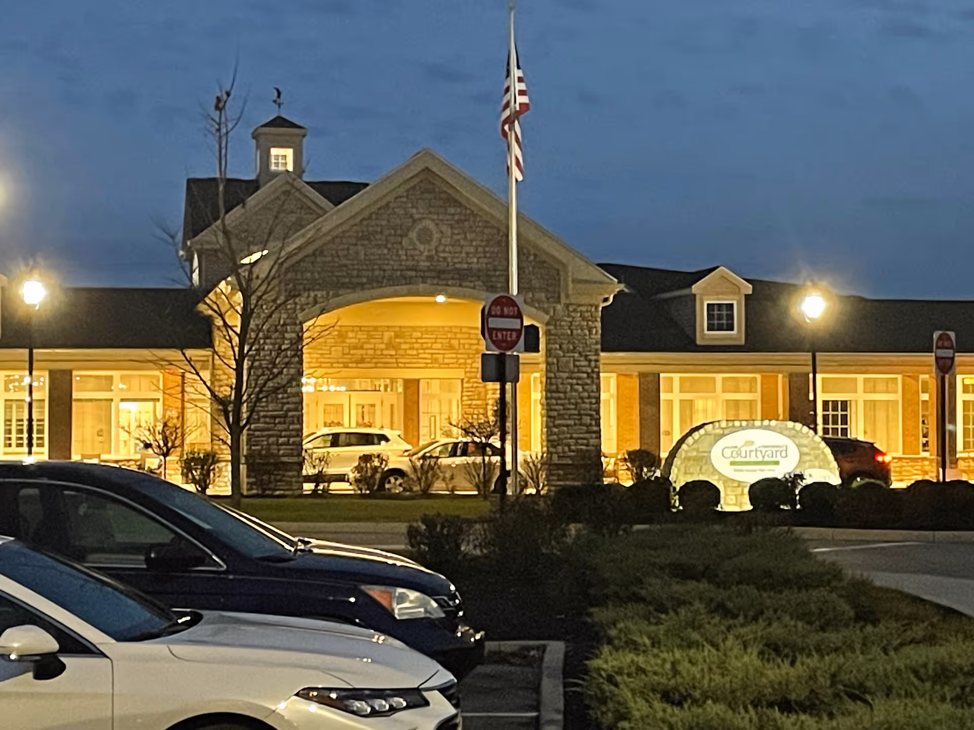Evening exterior view of The Courtyard at Centerville with illuminated entrance and parked cars