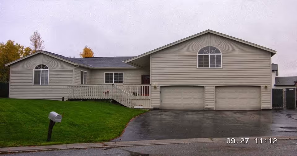 Beige, house-style assisted living home with a three-car garage and well-kept front lawn.