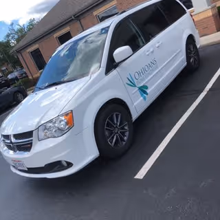 White van with Ohioans Home Healthcare logo parked in a lot near a brick building.