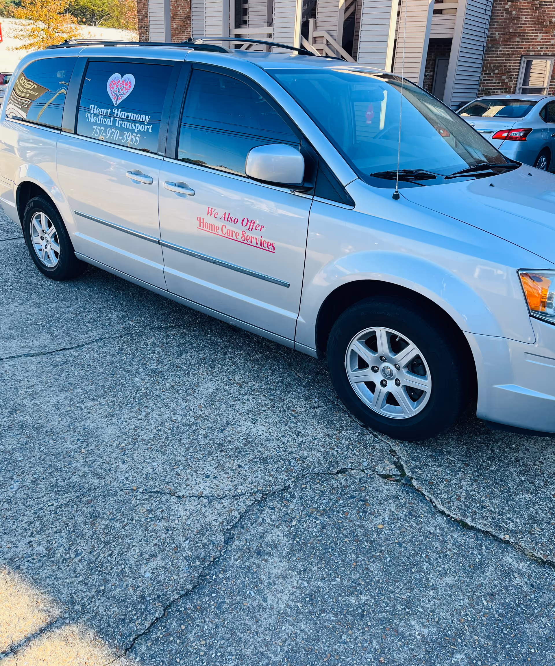 White branded van parked outside a senior facility with Heart Harmony Medical Transport logo