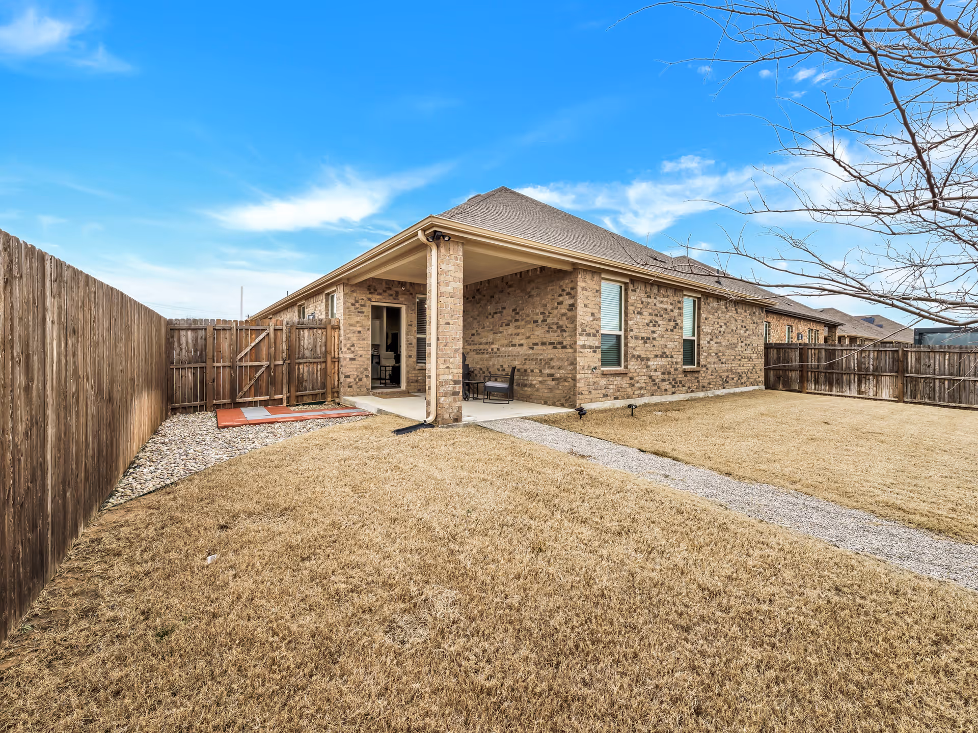 Backyard of Careessence Assisted Living with brick house, covered patio, fence, and gravel path
