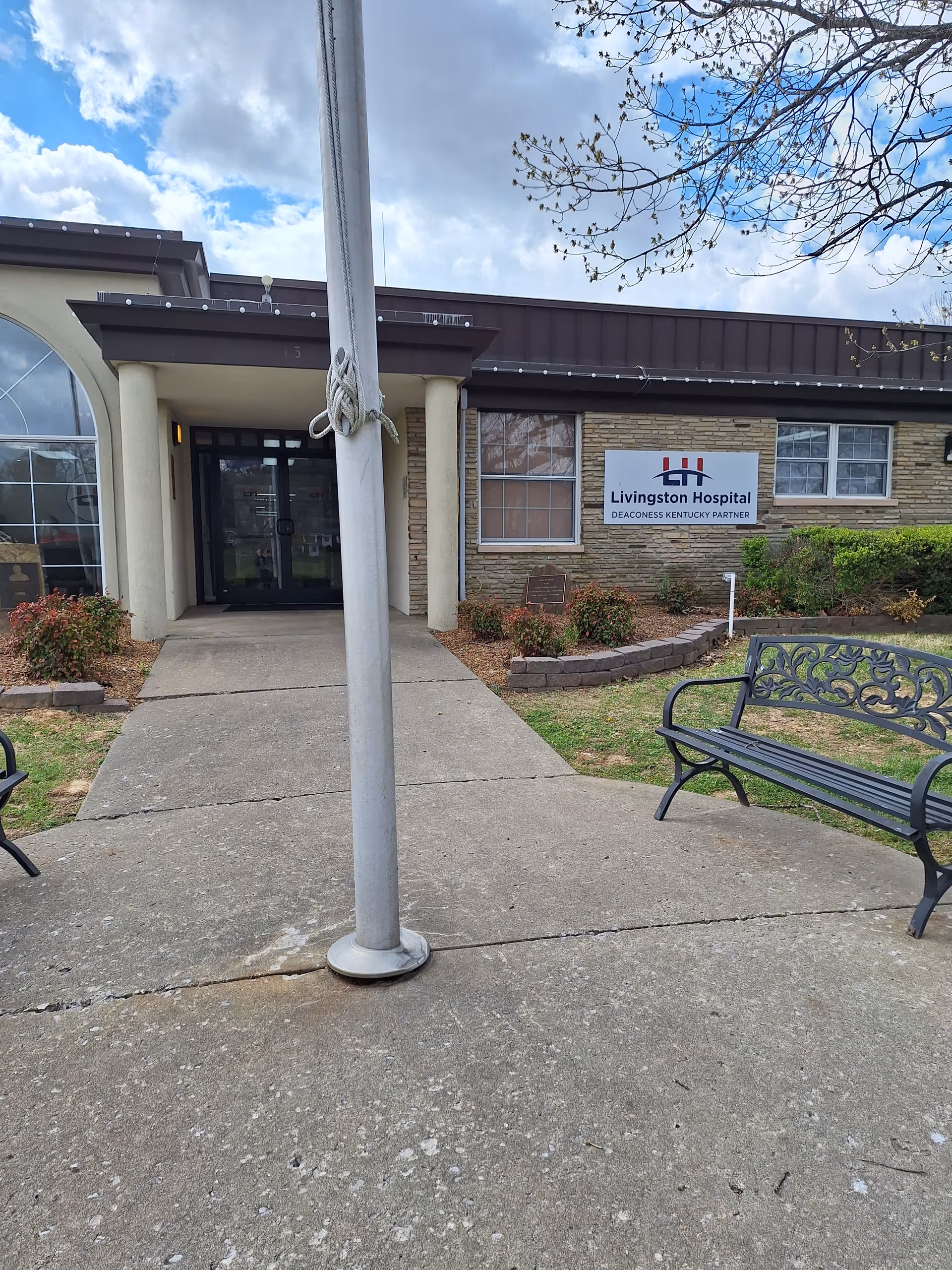 Exterior view of Livingston Hospital entrance with benches and flagpole.