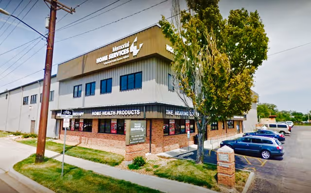 Exterior view of Memorial Home Services building with storefront signage and parked cars.