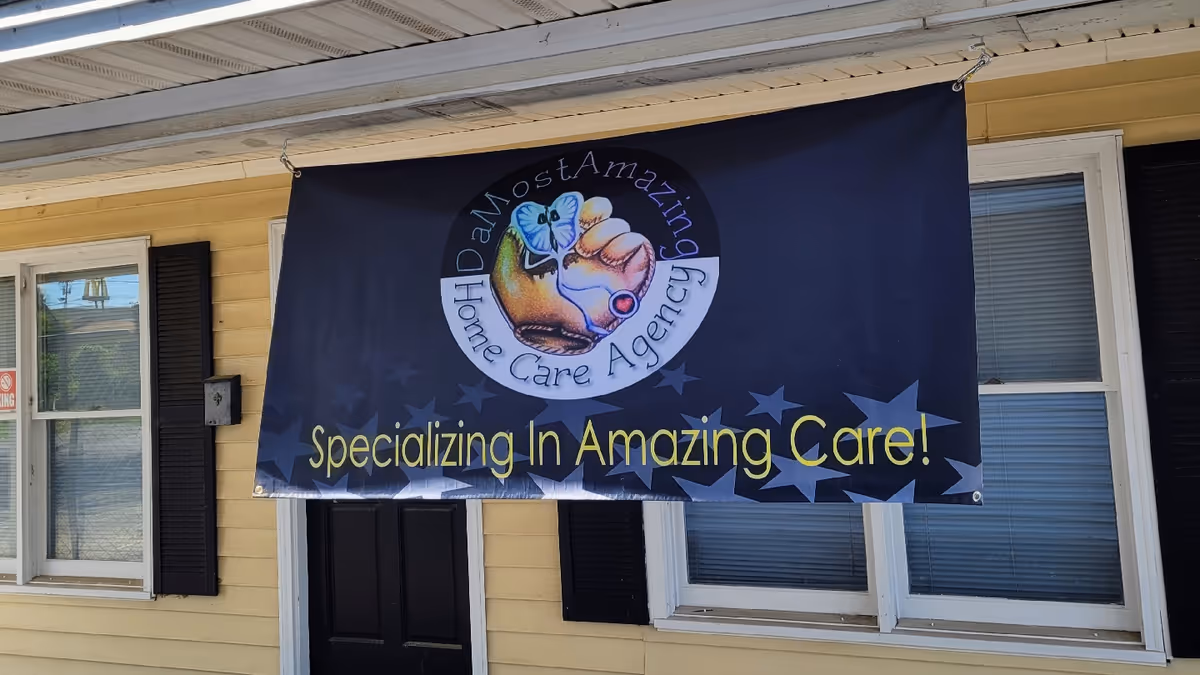 Front exterior of a yellow building with a large DaMostAmazing Home Care banner.