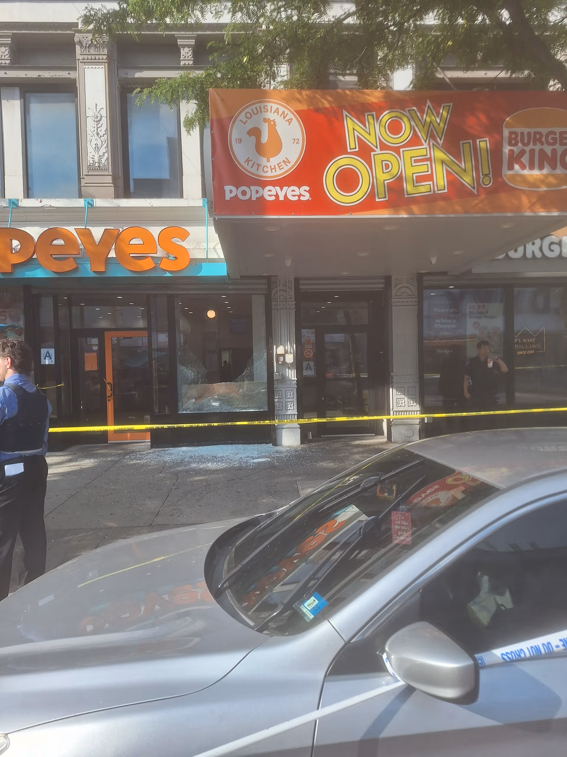 Exterior storefronts featuring Popeyes with a Now Open banner and yellow caution tape across the entrance.