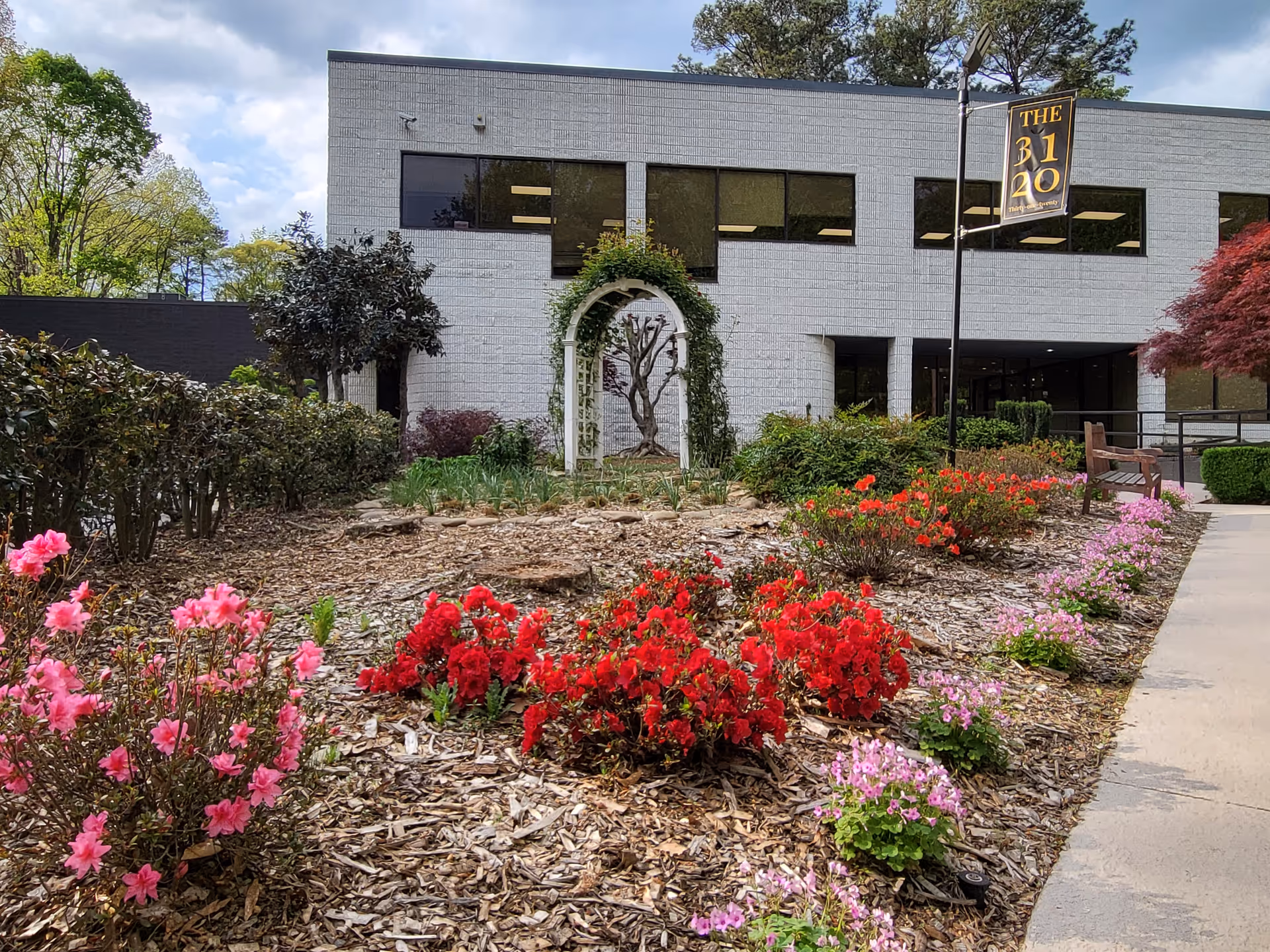 Exterior view of Joynus Care building with landscaped garden and bench along walkway.