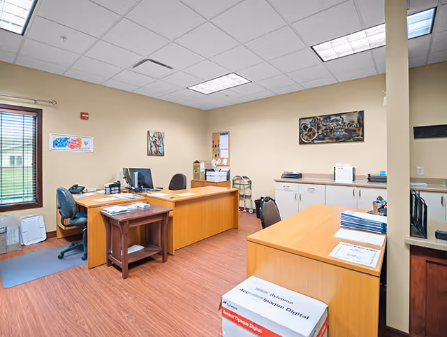 Office reception area with desks, computers, and cabinets in a senior living facility.