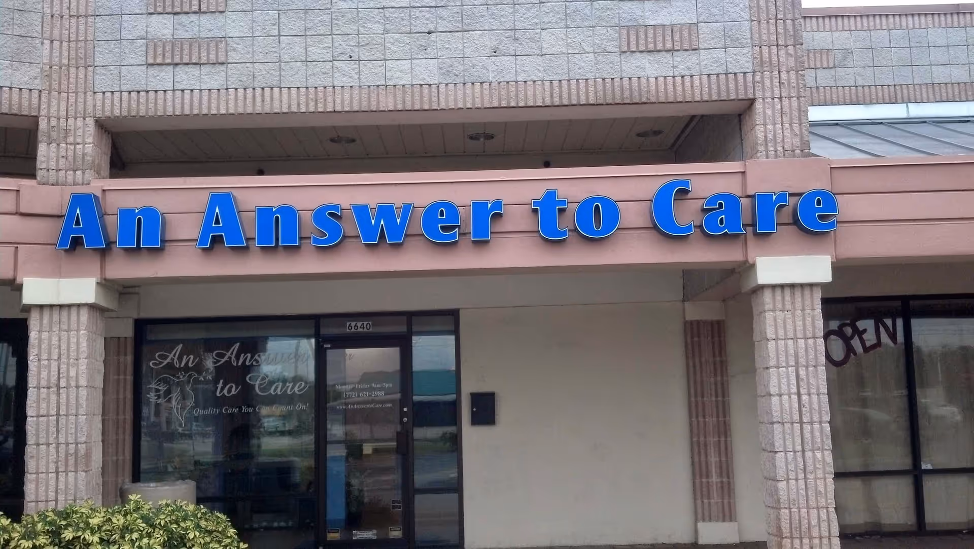 Exterior view of a building entrance with a blue An Answer to Care sign.