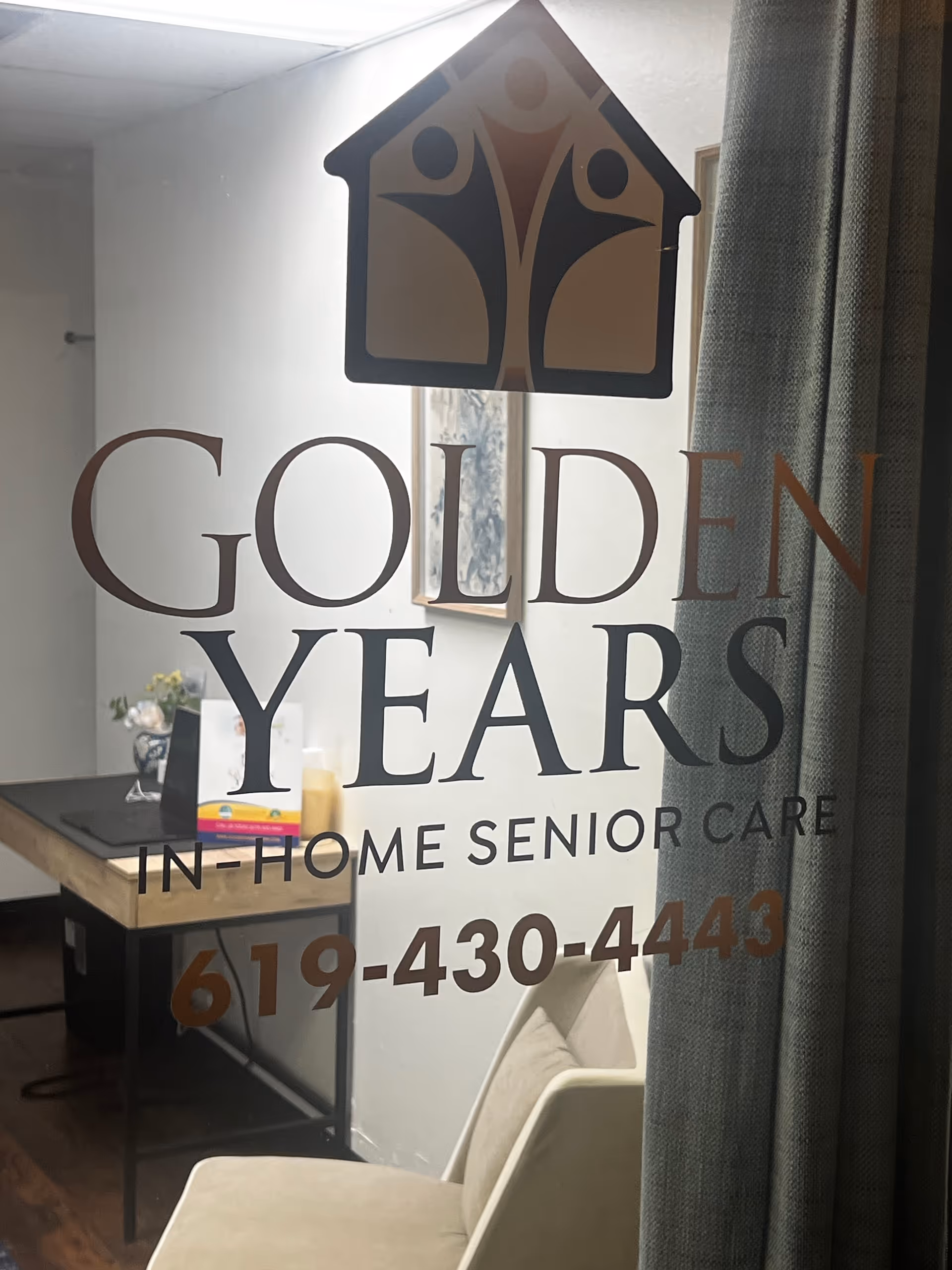 Glass door displays Golden Years In-Home Senior Care logo with office desk behind.