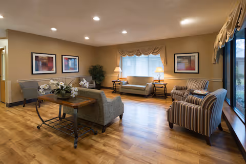 Cozy lounge-style living room with sofas, armchairs, lamps, and framed wall art.