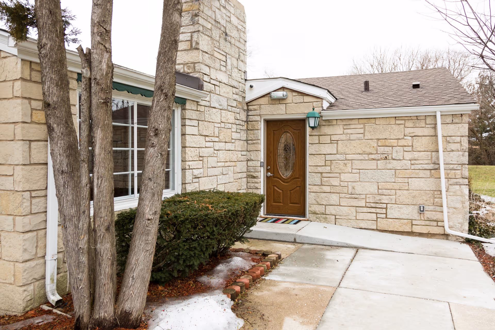 Exterior view of a stone senior living building with a wooden front door.