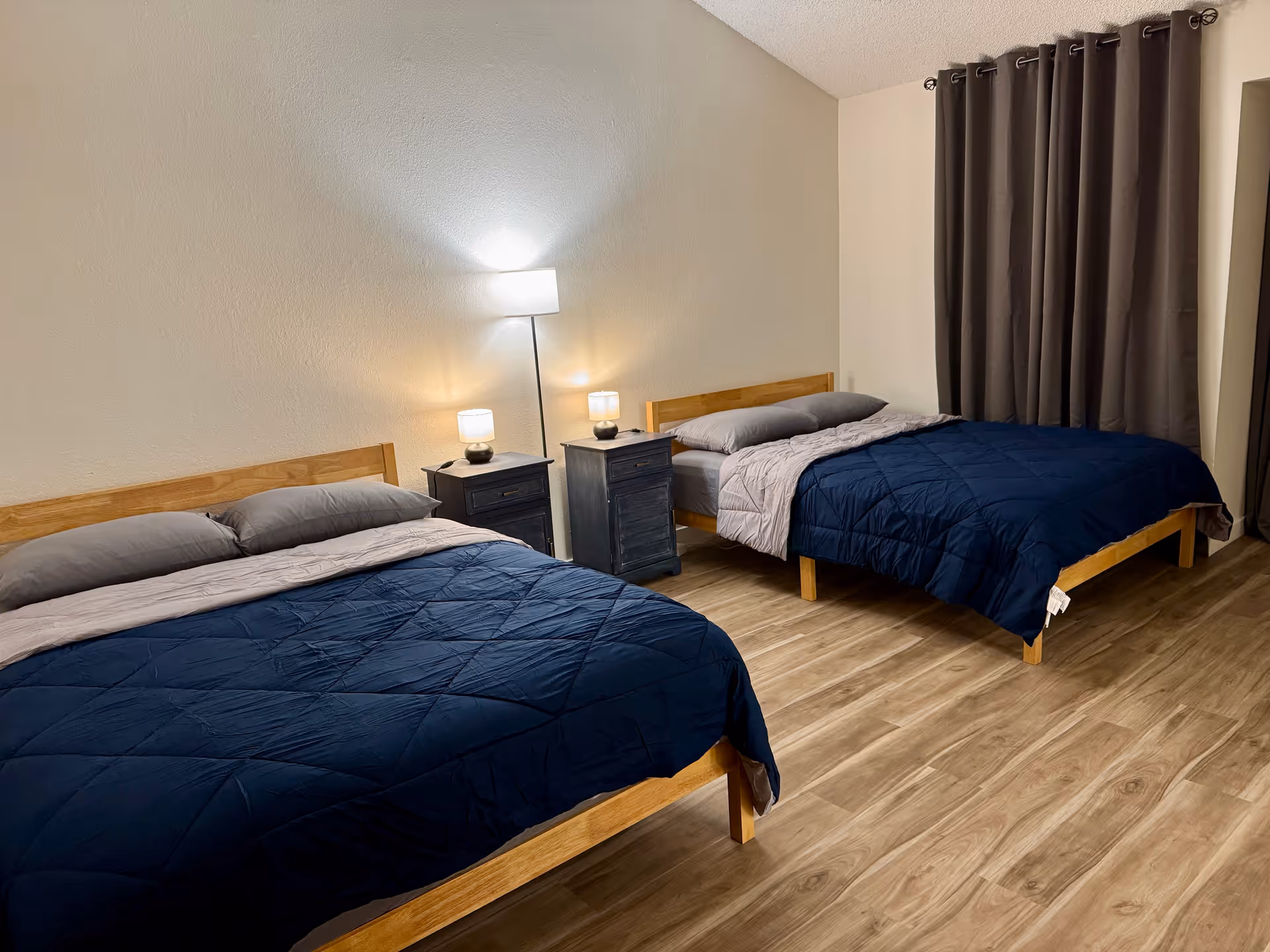 Two twin beds with navy quilts and matching nightstands in a tidy bedroom.
